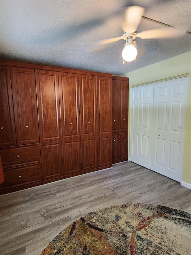 unfurnished bedroom with ceiling fan, light hardwood / wood-style floors, and a textured ceiling