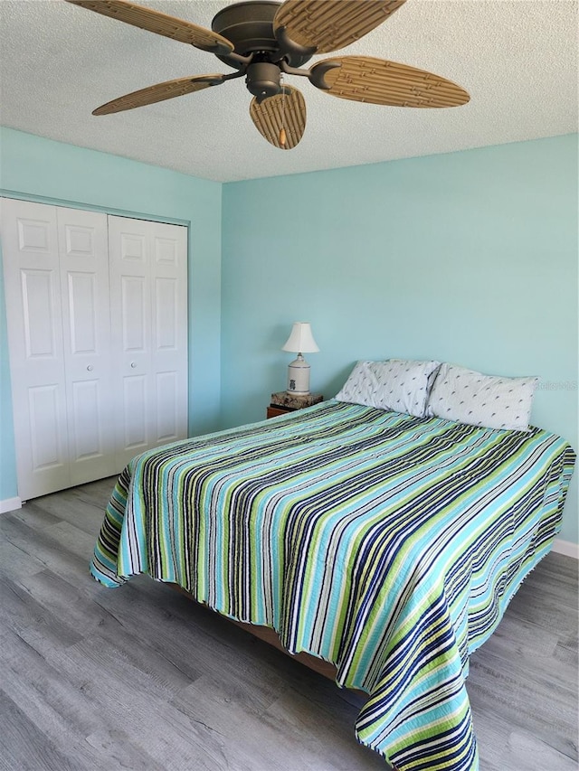 bedroom with a textured ceiling, ceiling fan, a closet, and hardwood / wood-style floors