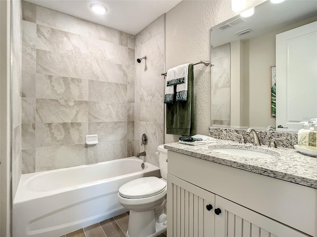 full bathroom with tile flooring, toilet, tiled shower / bath combo, and large vanity