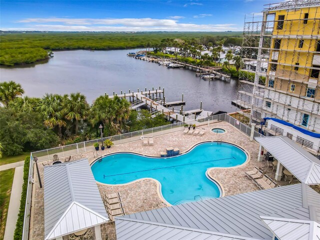 view of swimming pool featuring a water view, a boat dock, and a patio area