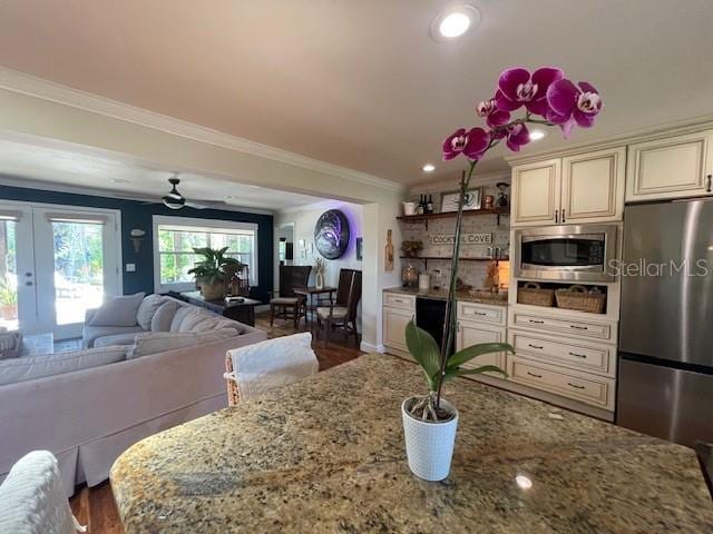 4606 Doris Dr, New Smyrna Beach, FL 32169 - kitchen featuring stainless steel appliances, cream cabinetry, ornamental molding, french doors, and light stone countertops