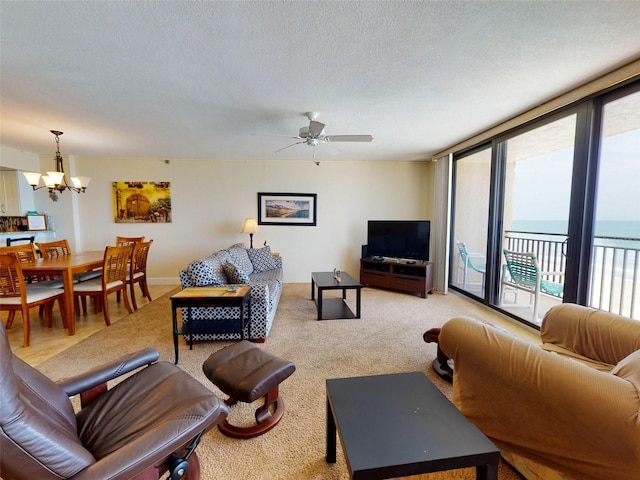 living room with a water view, light hardwood / wood-style floors, a textured ceiling, and ceiling fan with notable chandelier