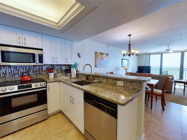 kitchen featuring kitchen peninsula, tasteful backsplash, stainless steel appliances, sink, and white cabinetry