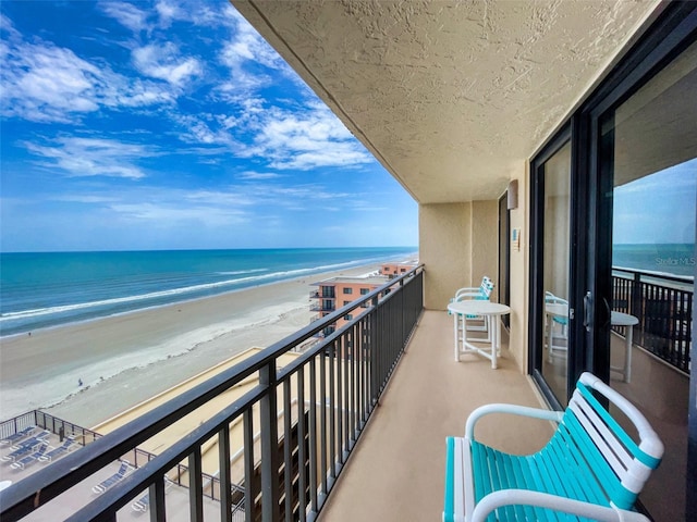 balcony featuring a view of the beach and a water view