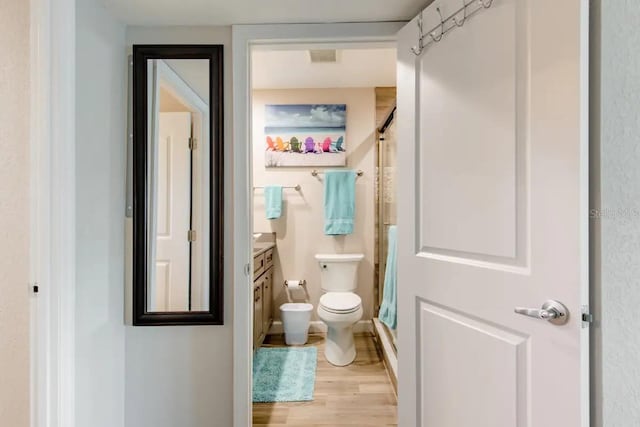 bathroom with walk in shower, vanity, toilet, and hardwood / wood-style floors