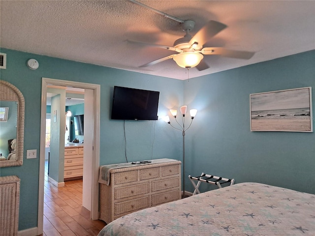 bedroom with a textured ceiling, hardwood / wood-style flooring, ceiling fan, and connected bathroom