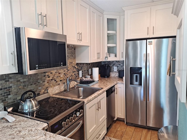 kitchen with light hardwood / wood-style floors, backsplash, sink, white cabinetry, and appliances with stainless steel finishes