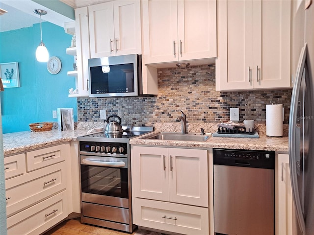 kitchen featuring stainless steel appliances, tasteful backsplash, white cabinetry, sink, and pendant lighting