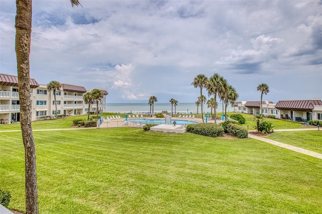 view of community featuring a lawn, a water view, and a pool