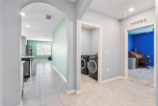 hallway featuring washing machine and dryer, a textured ceiling, and light tile patterned floors