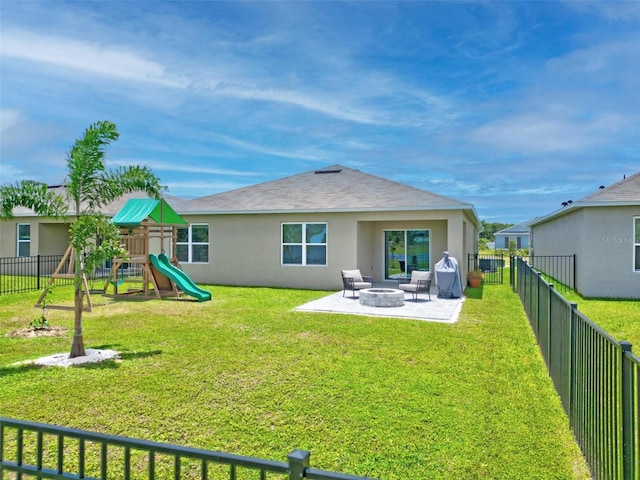 rear view of property with a lawn, a patio, a playground, and an outdoor fire pit