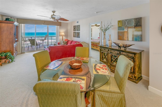 carpeted dining room featuring ceiling fan, a water view, and a textured ceiling