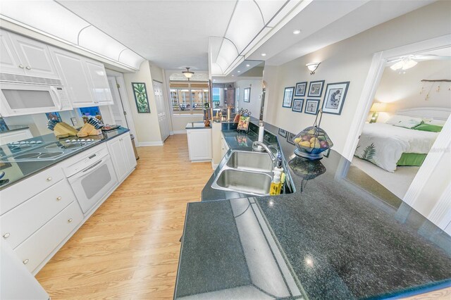 kitchen featuring white appliances, a center island with sink, sink, light hardwood / wood-style flooring, and white cabinetry