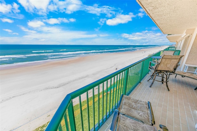 balcony featuring a view of the beach and a water view