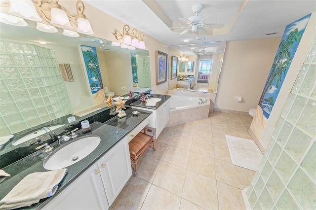 bathroom with vanity, tile patterned floors, ceiling fan, toilet, and a tray ceiling