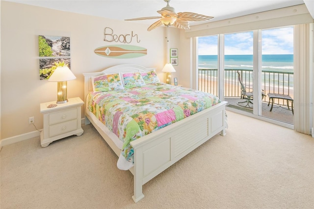 carpeted bedroom with access to exterior, ceiling fan, a water view, and a beach view