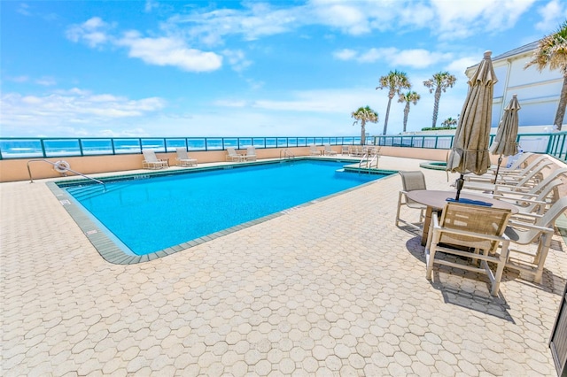 view of swimming pool featuring a water view and a patio