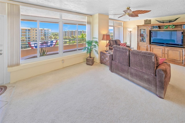 living room with carpet flooring, a textured ceiling, and ceiling fan