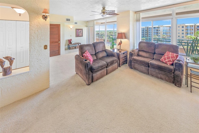 living room featuring light carpet, a textured ceiling, and ceiling fan