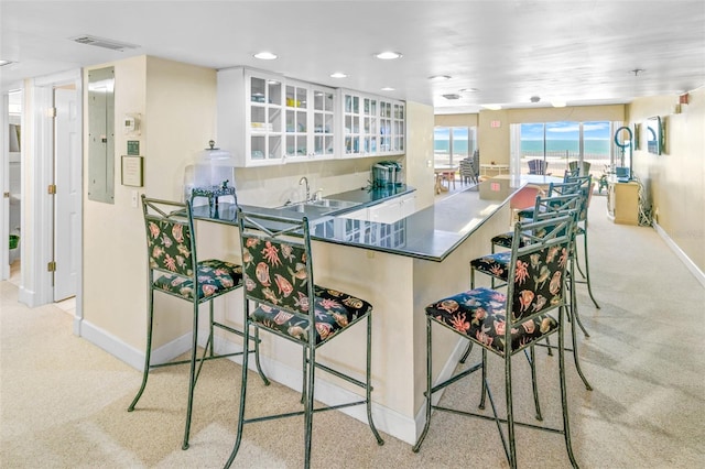 kitchen with a kitchen breakfast bar, kitchen peninsula, light carpet, and white cabinets