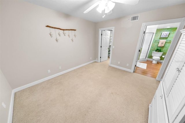 unfurnished bedroom with connected bathroom, light colored carpet, and ceiling fan