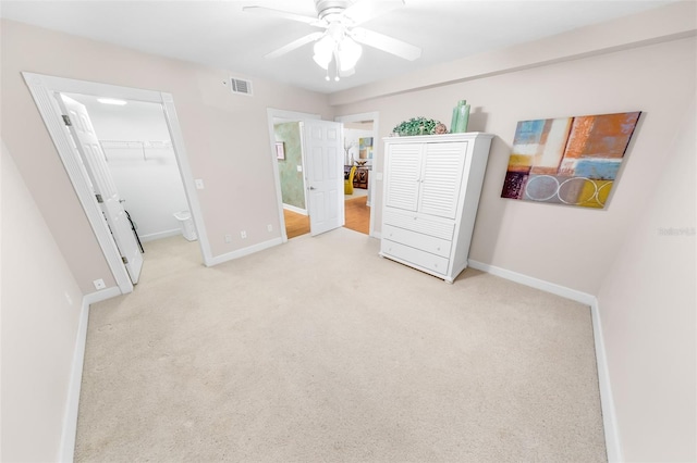 carpeted bedroom featuring a closet, ensuite bath, a spacious closet, and ceiling fan