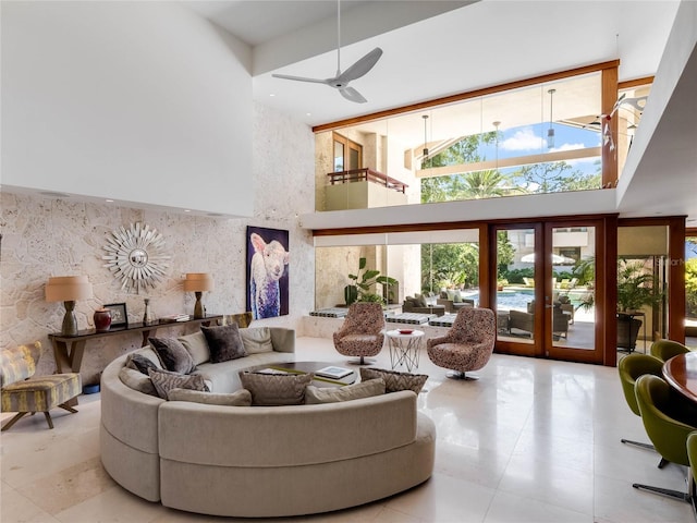 tiled living room featuring ceiling fan, a high ceiling, and french doors