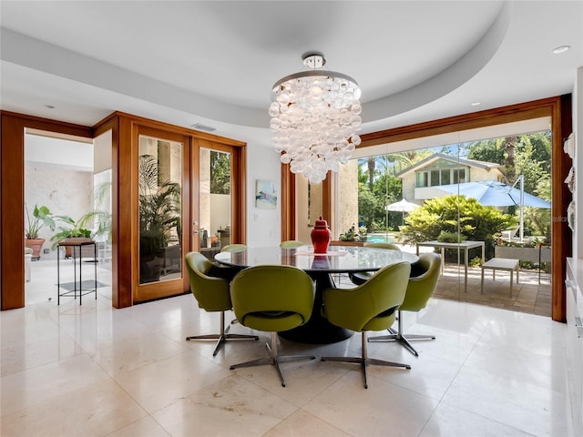 dining area with a tray ceiling, light tile patterned floors, a healthy amount of sunlight, and a notable chandelier