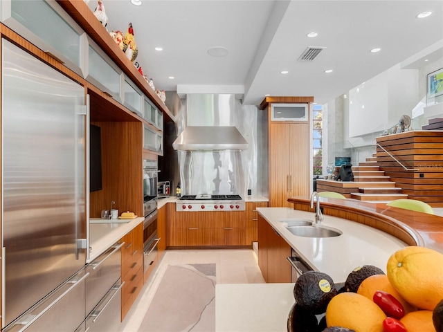 kitchen with sink, wall chimney exhaust hood, light tile patterned floors, tasteful backsplash, and stainless steel appliances