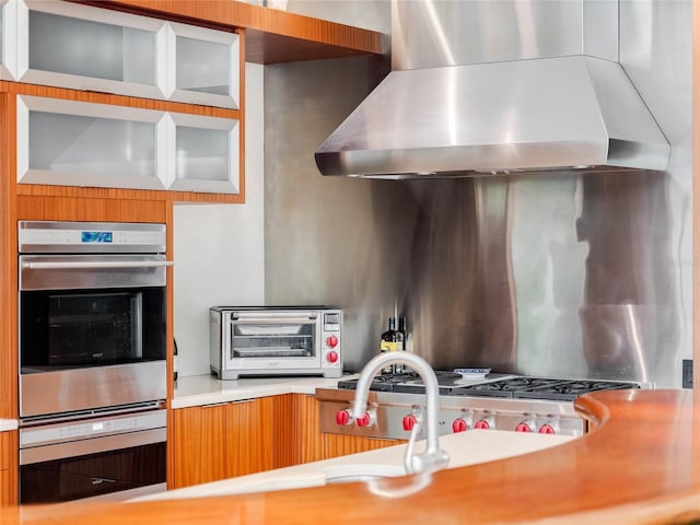 kitchen featuring stainless steel double oven and wall chimney range hood