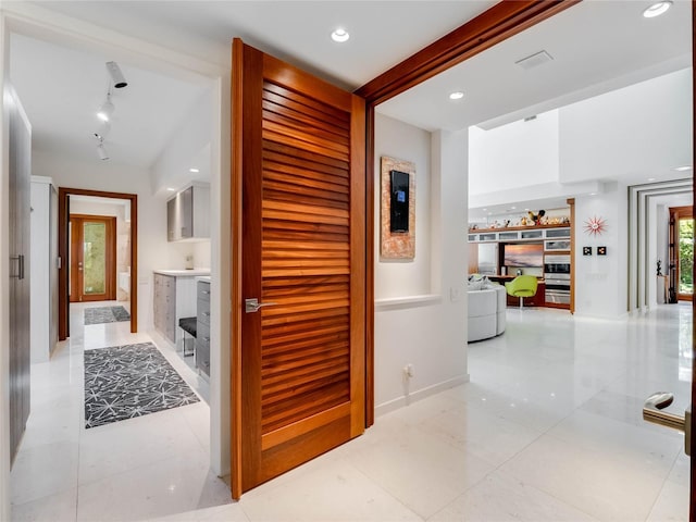 hallway with beam ceiling and light tile patterned floors