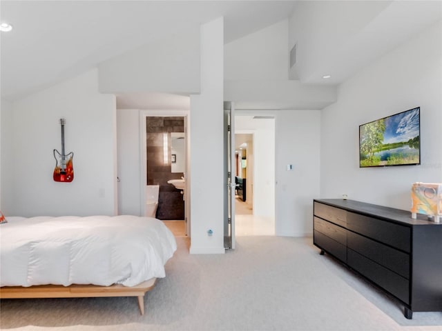 bedroom featuring light carpet, ensuite bath, and lofted ceiling