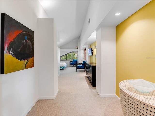 corridor featuring light colored carpet and lofted ceiling