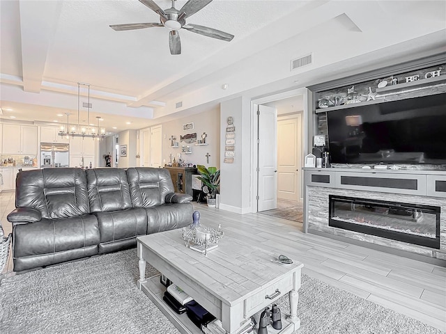 living area with visible vents, beamed ceiling, light wood-style floors, baseboards, and ceiling fan