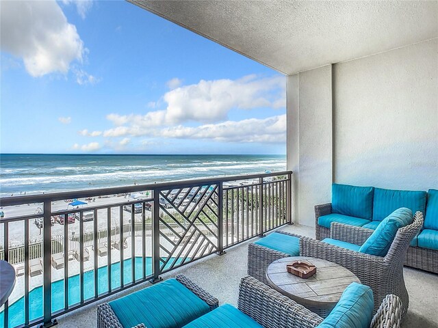 balcony with an outdoor hangout area, a beach view, and a water view