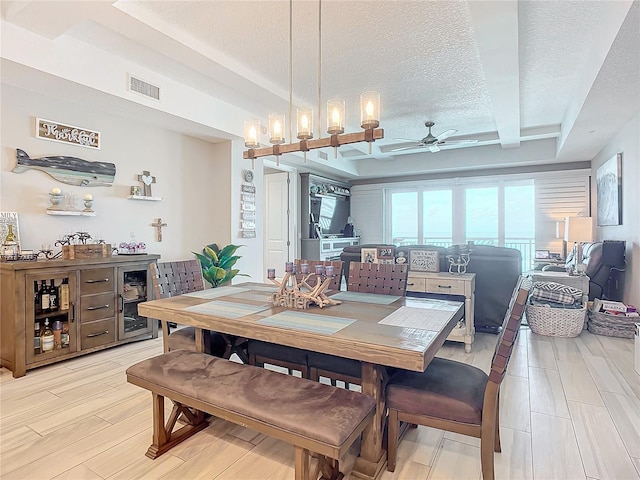 dining space featuring visible vents, beam ceiling, ceiling fan, light wood-style floors, and a textured ceiling