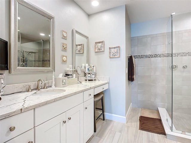 bathroom with a stall shower, vanity, and baseboards