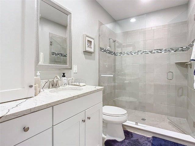 bathroom with a stall shower, toilet, and vanity