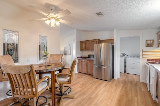 kitchen featuring a textured ceiling, lofted ceiling, stainless steel appliances, and light hardwood / wood-style flooring