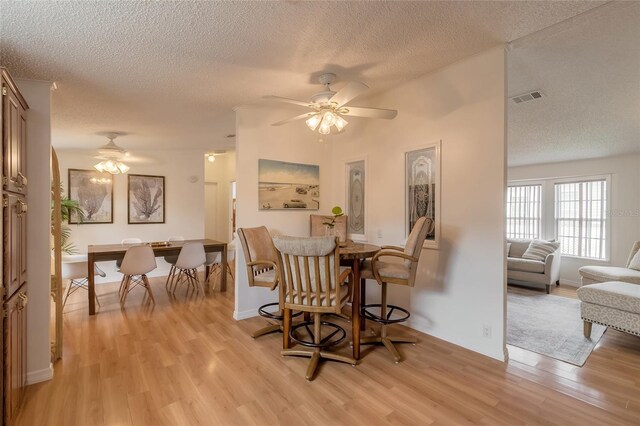 dining room featuring ceiling fan, a textured ceiling, and light hardwood / wood-style flooring