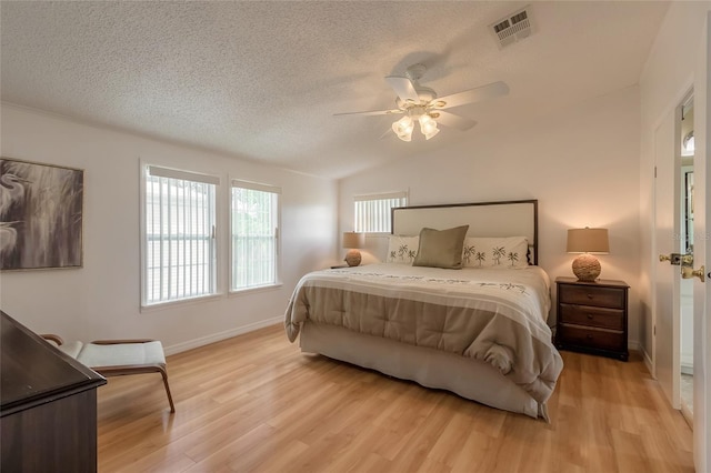 bedroom with a textured ceiling, ceiling fan, light hardwood / wood-style floors, and lofted ceiling