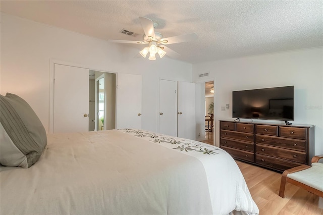 bedroom with a textured ceiling, light hardwood / wood-style floors, and ceiling fan