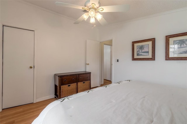 bedroom featuring ceiling fan, crown molding, a textured ceiling, and light wood-type flooring