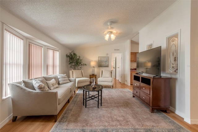 living room featuring a textured ceiling, ceiling fan, light hardwood / wood-style flooring, and lofted ceiling