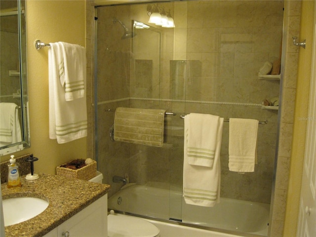 full bathroom featuring vanity, shower / bath combination with glass door, and toilet