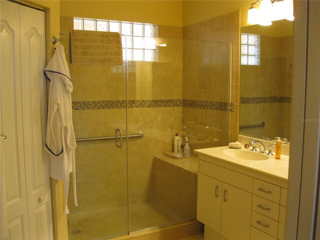 bathroom featuring a shower with door and vanity