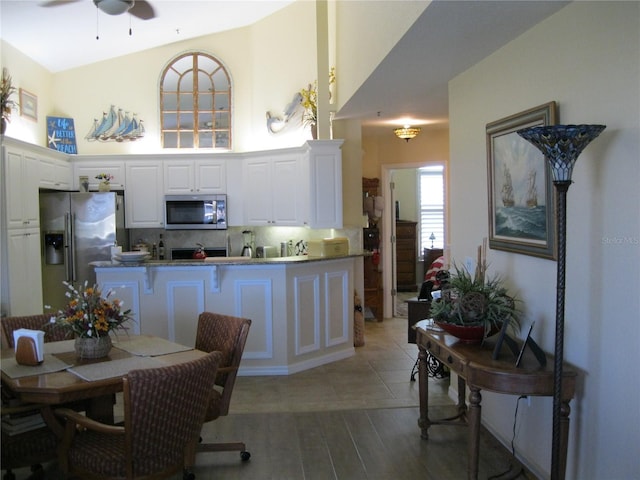 kitchen with ceiling fan, white cabinets, kitchen peninsula, backsplash, and stainless steel appliances