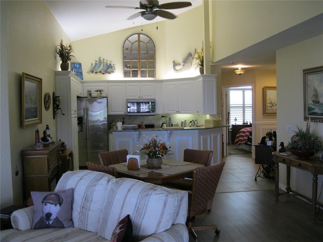 dining space featuring hardwood / wood-style floors, high vaulted ceiling, and ceiling fan