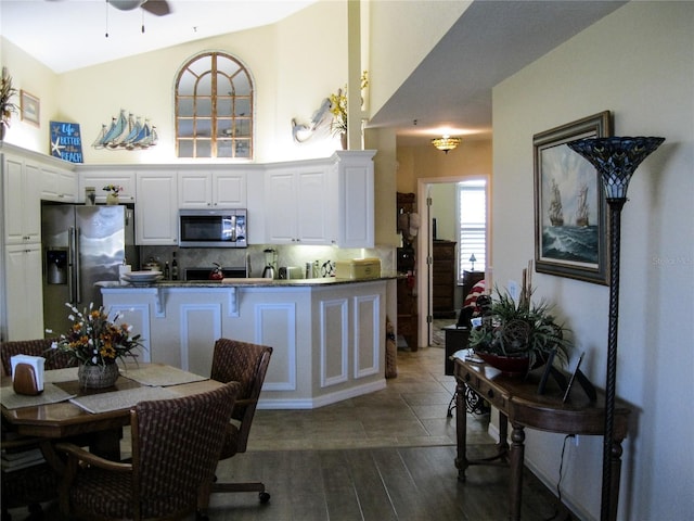 434 Bouchelle Dr Unit 304, New Smyrna Beach, FL 32169 - kitchen with appliances with stainless steel finishes, decorative backsplash, white cabinetry, dark countertops, and dark wood-type flooring