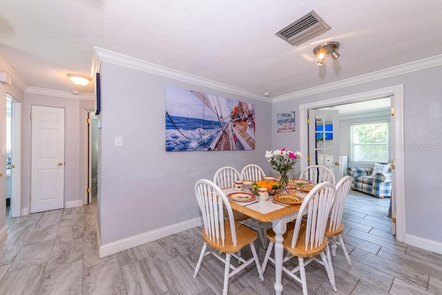 dining area with ornamental molding and a textured ceiling